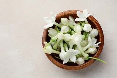 Photo of Bowl with jasmine flowers on beige table, top view. Space for text