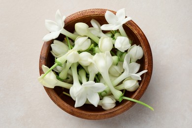 Photo of Bowl with jasmine flowers on beige table, top view