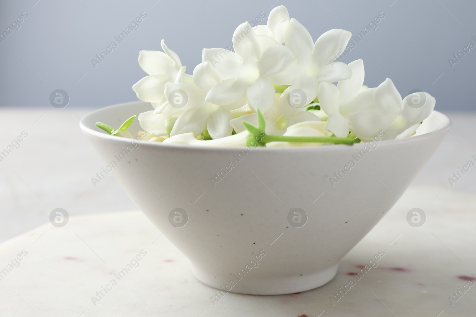 Beautiful jasmine flowers in bowl on table, closeup Photo of Beautiful jasmine flowers in bowl on table, closeup