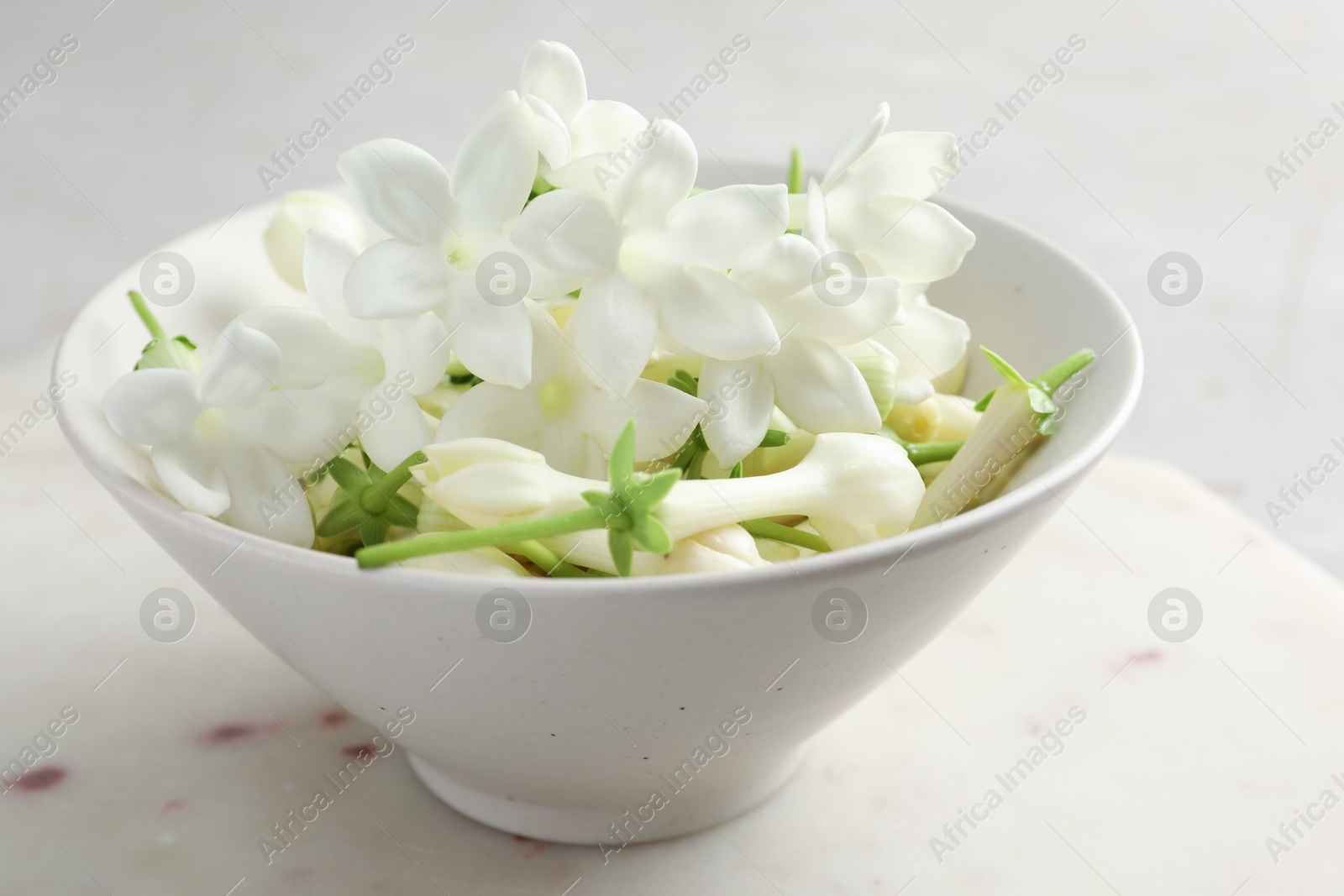 Beautiful jasmine flowers in bowl on table, closeup Photo of Beautiful jasmine flowers in bowl on table, closeup