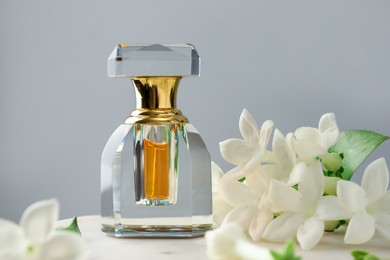 Photo of Perfume and jasmine flowers on table against grey background, closeup