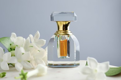 Photo of Perfume and jasmine flowers on table against grey background, closeup