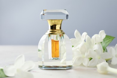 Photo of Perfume and jasmine flowers on table against grey background, closeup