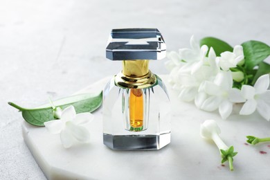 Photo of Perfume and jasmine flowers on light grey table, closeup
