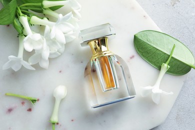 Photo of Perfume and jasmine flowers on light grey table, top view
