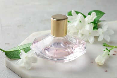Photo of Perfume and jasmine flowers on light grey table, closeup
