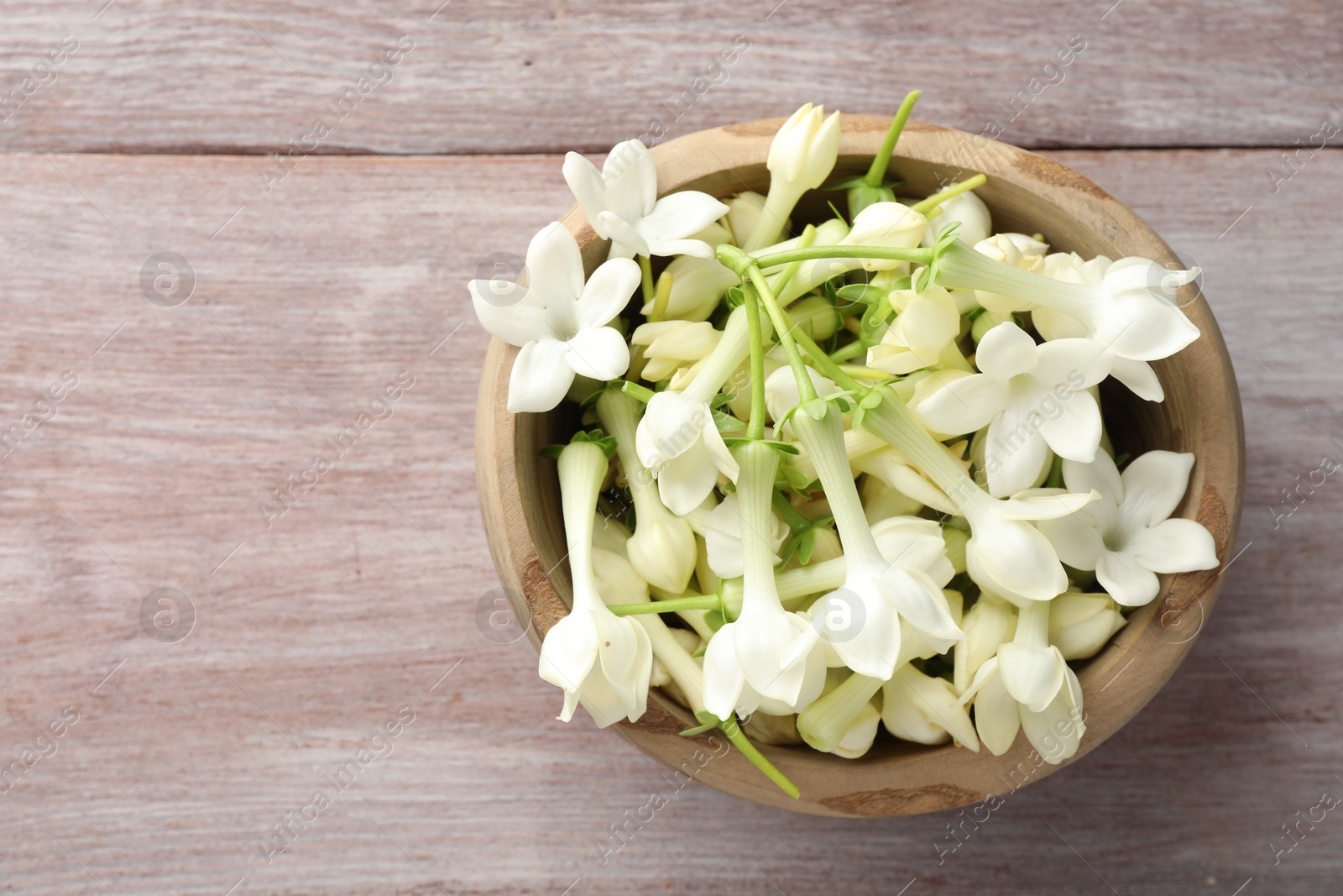 Beautiful jasmine flowers in bowl on wooden table, top view. Space for text Photo of Beautiful jasmine flowers in bowl on wooden table, top view. Space for text