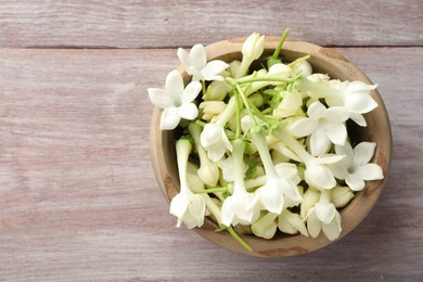 Photo of Beautiful jasmine flowers in bowl on wooden table, top view. Space for text