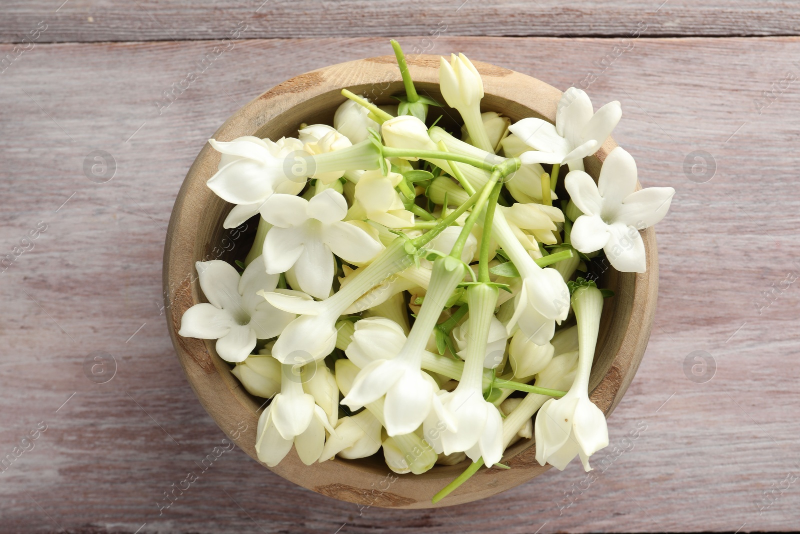 Beautiful jasmine flowers in bowl on wooden table, top view Photo of Beautiful jasmine flowers in bowl on wooden table, top view