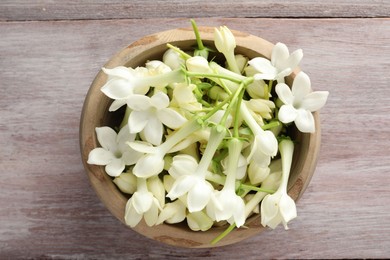 Photo of Beautiful jasmine flowers in bowl on wooden table, top view