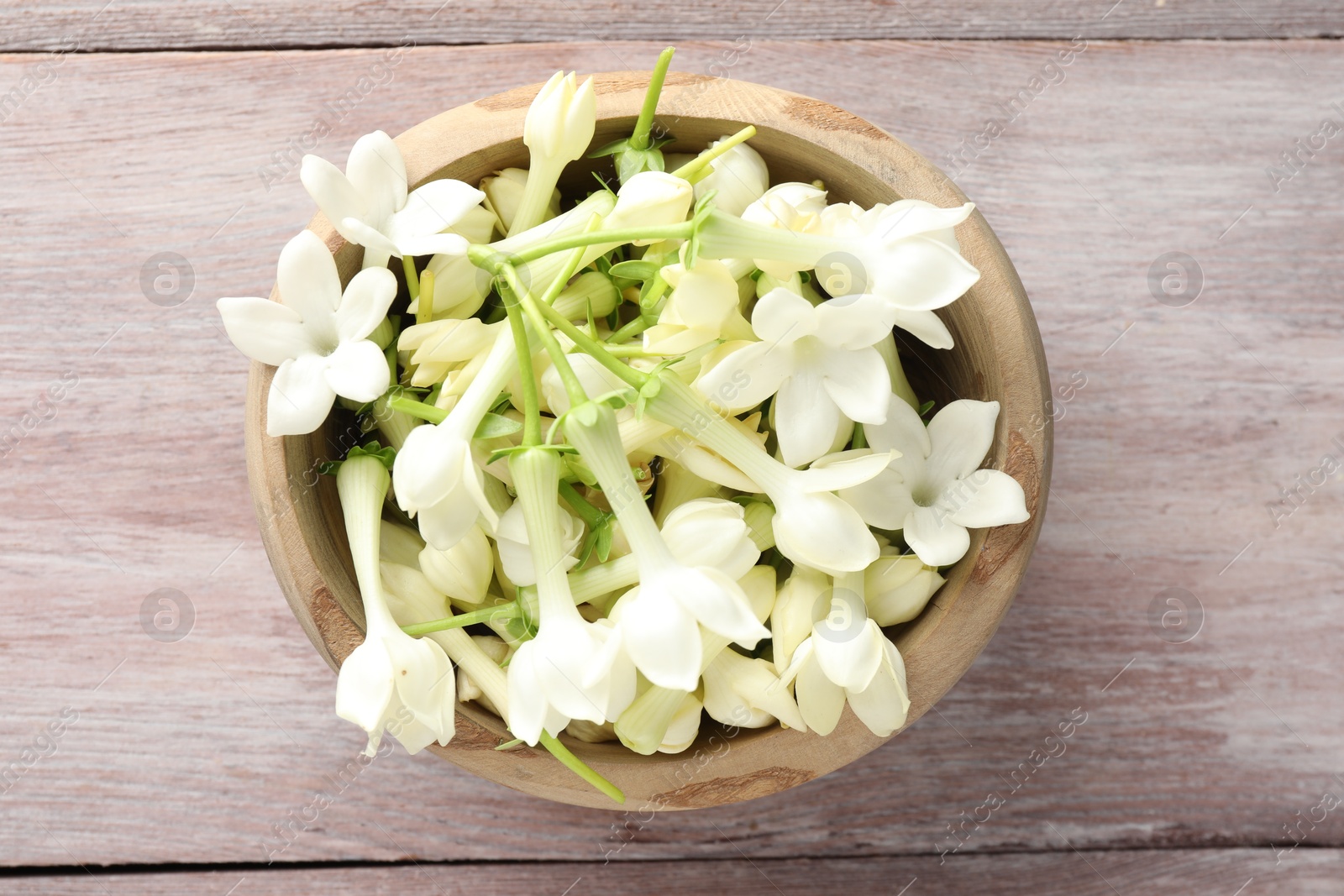 Beautiful jasmine flowers in bowl on wooden table, top view Photo of Beautiful jasmine flowers in bowl on wooden table, top view