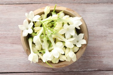 Photo of Beautiful jasmine flowers in bowl on wooden table, top view