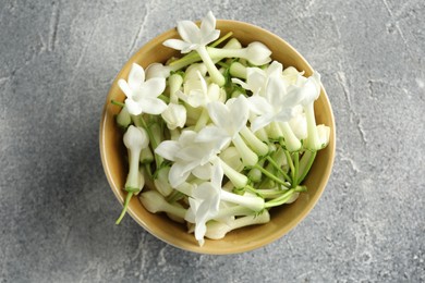 Photo of Beautiful jasmine flowers in bowl on grey table, top view