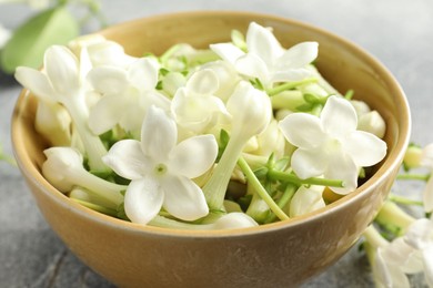 Photo of Beautiful jasmine flowers in bowl on table, closeup