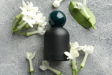 Photo of Perfume and jasmine flowers on grey table, flat lay