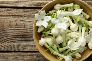 Photo of Beautiful jasmine flowers in bowl on wooden table, top view. Space for text