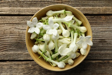 Photo of Beautiful jasmine flowers in bowl on wooden table, top view