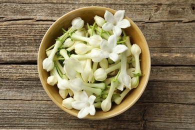 Photo of Beautiful jasmine flowers in bowl on wooden table, top view