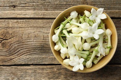 Photo of Beautiful jasmine flowers in bowl on wooden table, top view. Space for text
