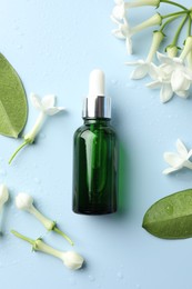Photo of Bottle of essential oil, jasmine flowers and green leaves on light blue background, flat lay
