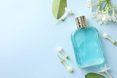 Photo of Perfume and jasmine flowers on light blue background, flat lay. Space for text