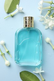 Photo of Perfume and jasmine flowers on light blue background, flat lay