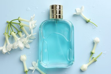Photo of Perfume and jasmine flowers on light blue background, flat lay