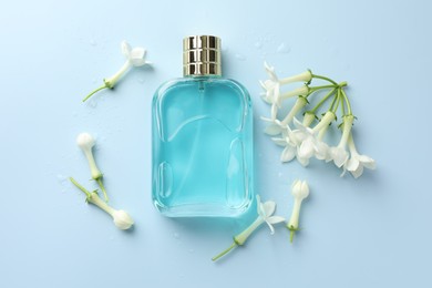 Photo of Perfume and jasmine flowers on light blue background, flat lay