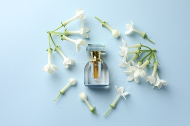 Photo of Perfume and jasmine flowers on light blue background, flat lay