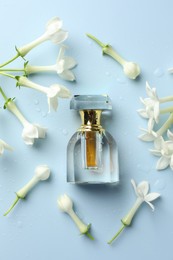 Photo of Perfume and jasmine flowers on light blue background, flat lay