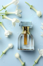 Photo of Perfume and jasmine flowers on light blue background, flat lay