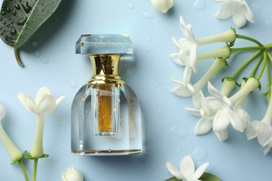 Photo of Perfume and jasmine flowers on light blue background, flat lay