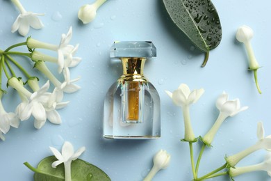 Photo of Perfume and jasmine flowers on light blue background, flat lay