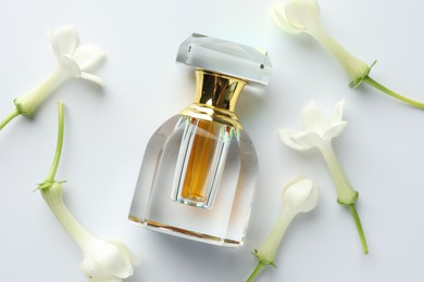 Photo of Perfume and jasmine flowers on white background, flat lay