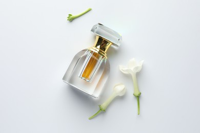Photo of Perfume and jasmine flowers on white background, flat lay