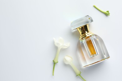 Photo of Perfume and jasmine flowers on white background, flat lay. Space for text