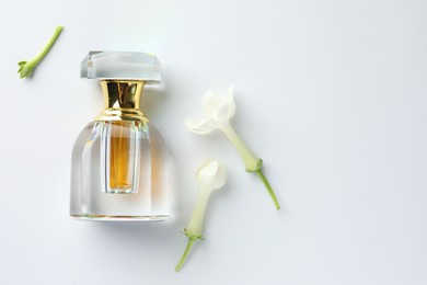 Photo of Perfume and jasmine flowers on white background, flat lay. Space for text