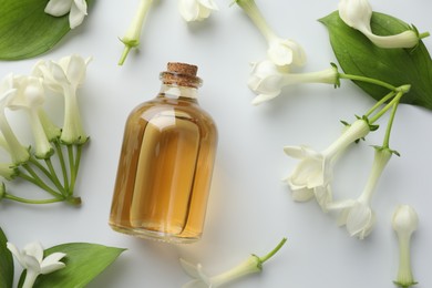 Photo of Bottle of essential oil, jasmine flowers and green leaves on white background, flat lay