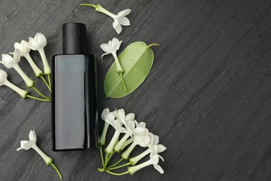 Photo of Perfume, jasmine flowers and green leaf on black table, flat lay. Space for text
