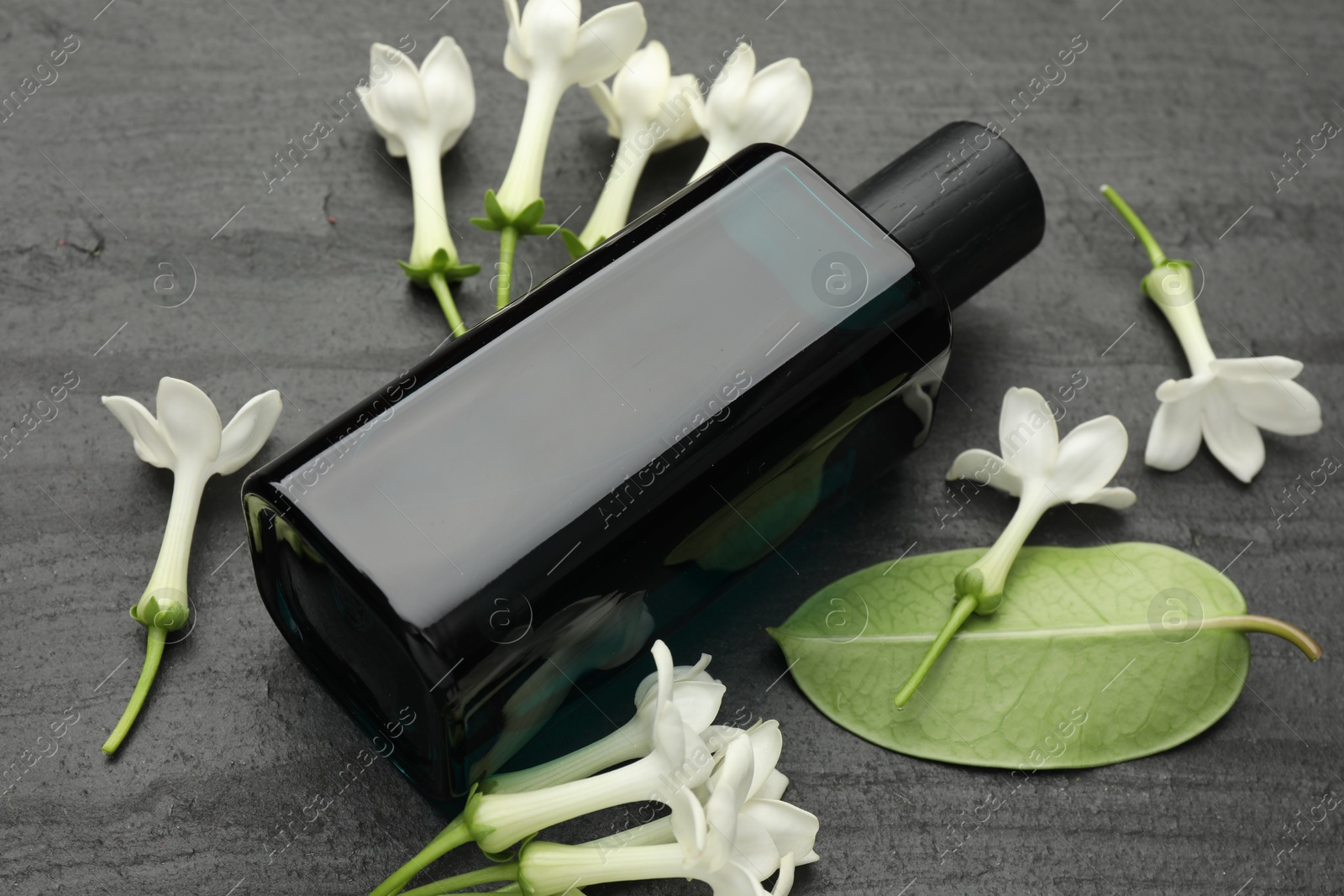 Perfume, jasmine flowers and green leaf on black table, closeup Photo of Perfume, jasmine flowers and green leaf on black table, closeup