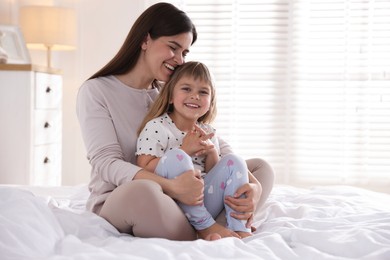 Photo of Mother and daughter on bed at home. Space for text
