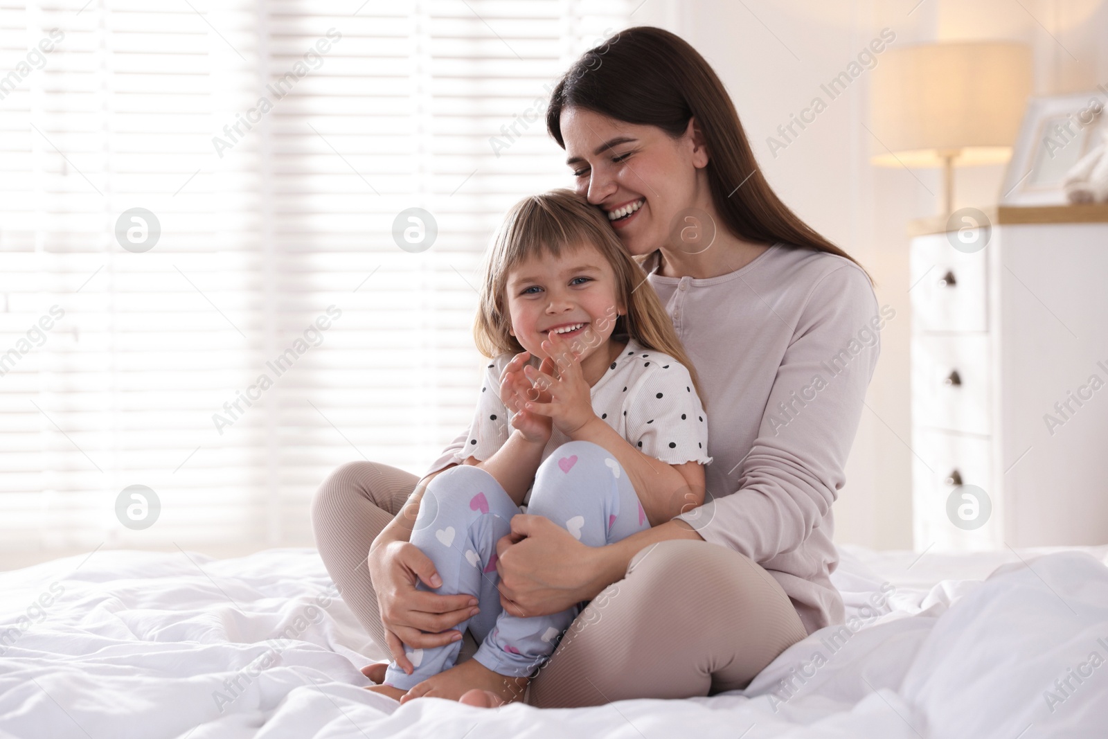Mother and daughter on bed at home. Space for text Photo of Mother and daughter on bed at home. Space for text