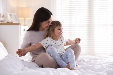 Photo of Mother and daughter having fun on bed at home. Space for text