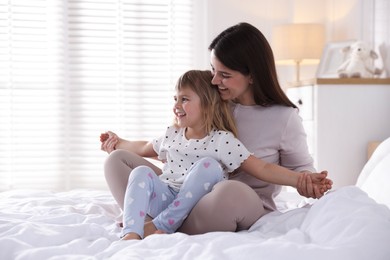 Photo of Mother and daughter having fun on bed at home. Space for text