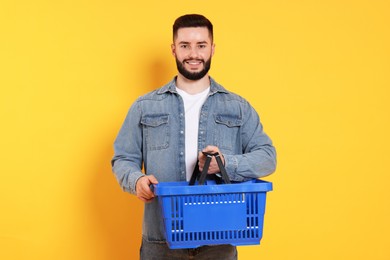 Photo of Man with empty shopping basket on orange background
