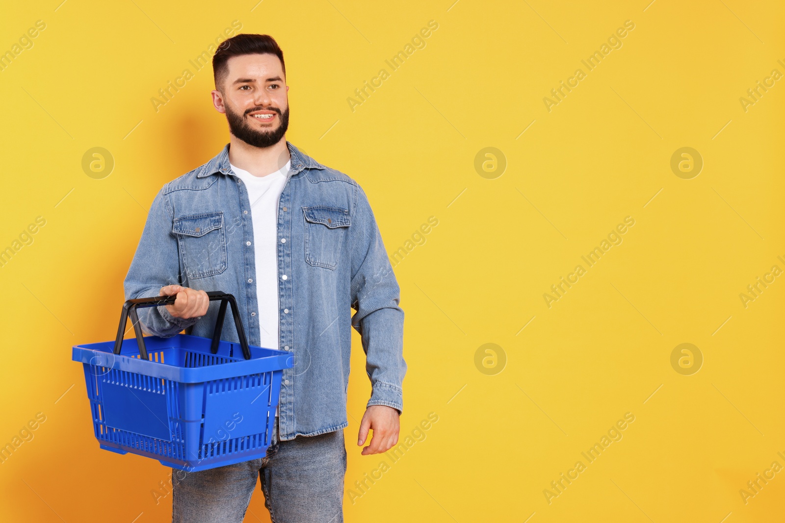 Man with empty shopping basket on orange background, space for text Photo of Man with empty shopping basket on orange background, space for text