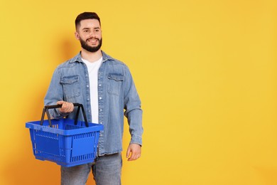 Photo of Man with empty shopping basket on orange background, space for text
