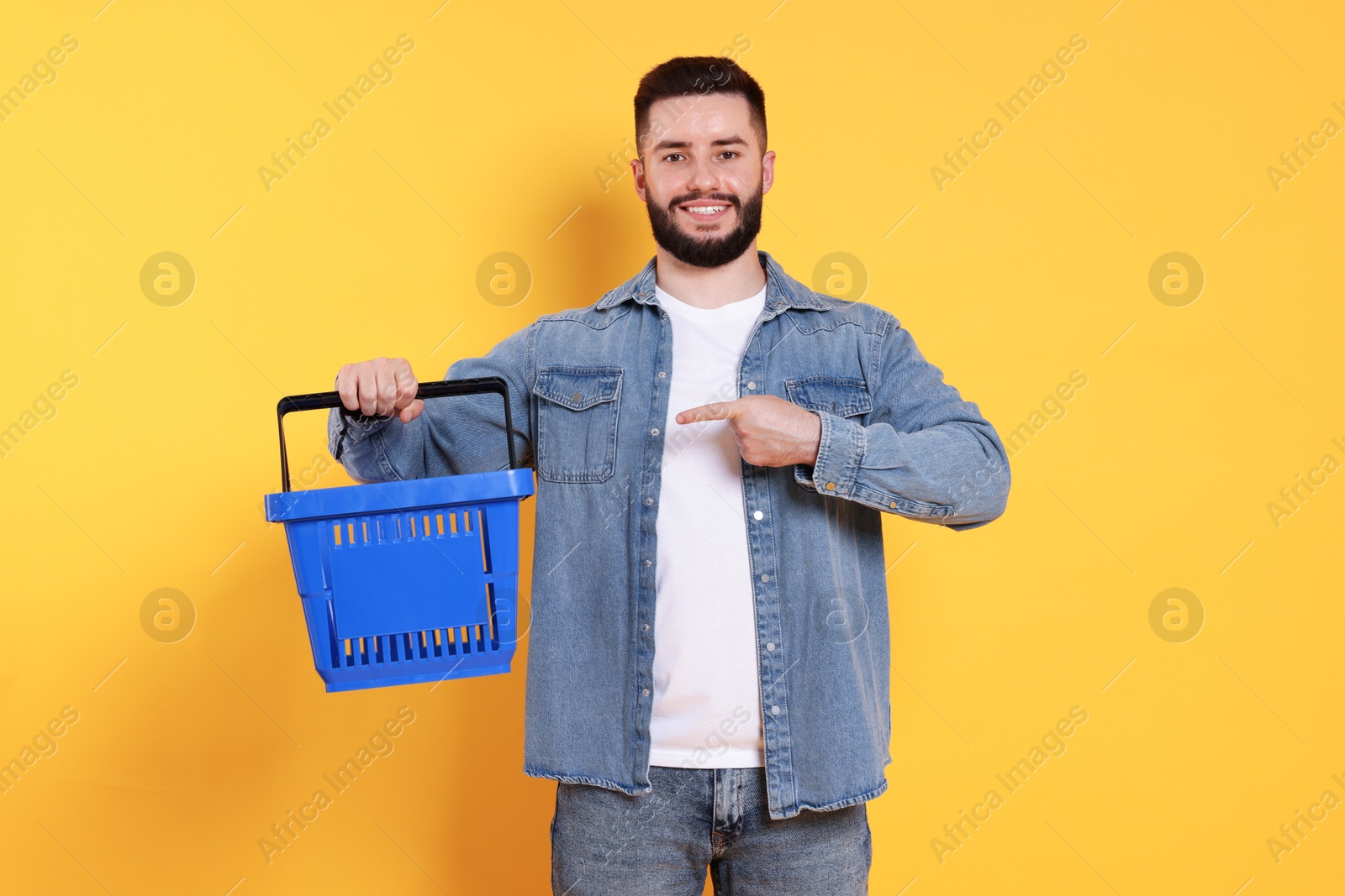 Man with empty shopping basket on orange background Photo of Man with empty shopping basket on orange background