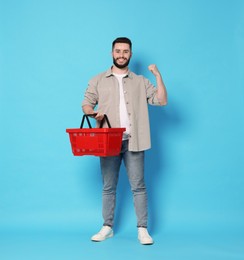 Photo of Man with empty shopping basket on light blue background