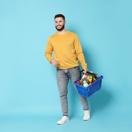 Photo of Man with shopping basket full of products on light blue background